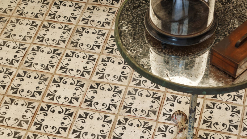 A vintage-style glass-top table with a dark ornate metal frame and reflective surface in moroccan kitchen tiles collection