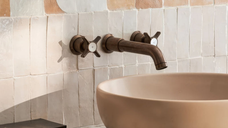 Antique bronze wall-mounted faucet with cross-shaped handles and curved spout in Moroccan wall tiles collection