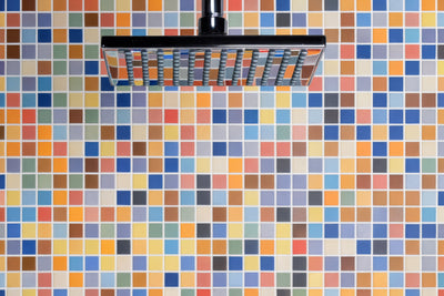 Modern chrome rectangular showerhead with multiple spray nozzles in a mosaic bathroom tiles collection
