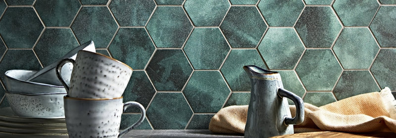 Stoneware ceramic mugs with speckled gray and white glaze stacked beside a matching pitcher on rustic wood surface nebula tiles
