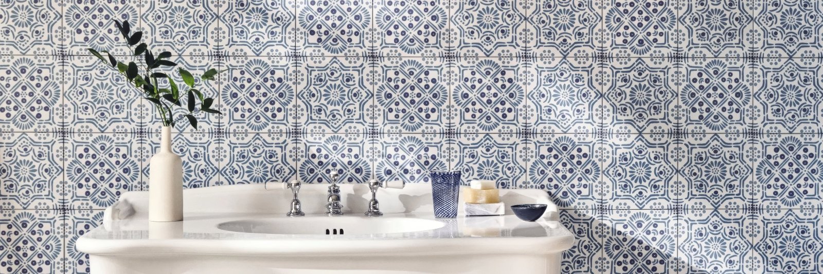 White ceramic pedestal sink with silver faucets and matching white countertop from nina campbell tile collection