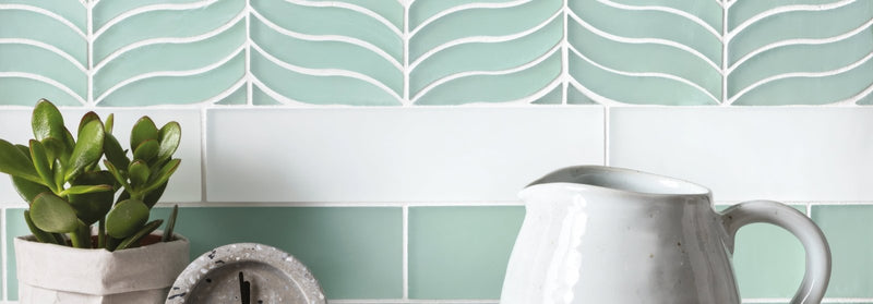 A matte white ceramic pitcher with a smooth curved handle and flared spout in the Nordic Glass Tiles collection