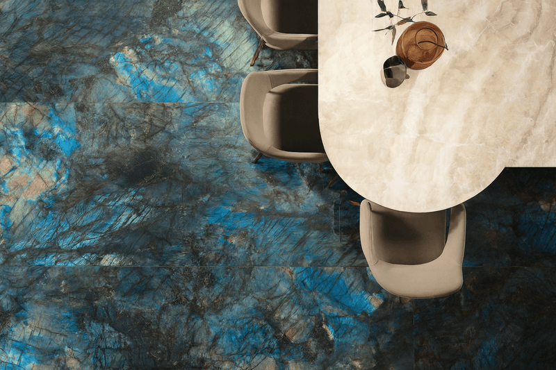 The table features a sleek oval marble surface with soft beige and white veining in the onyx effect floor tiles collection