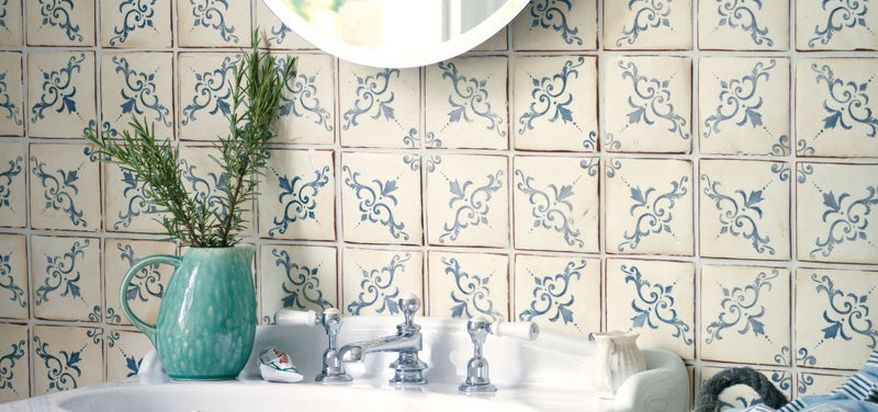 A turquoise ceramic pitcher with handle holding fresh green rosemary from the paris tiles collection