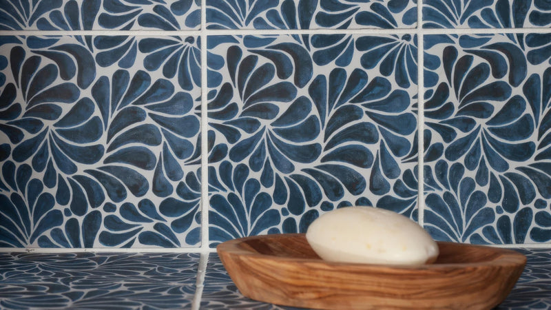 A creamy white soap bar in a rustic olive wood bowl paired with patterned wall tiles display