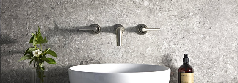 Modern matte-finished chrome faucet with sleek minimalist design mounted above a white ceramic sink from Pebble Beach Porcelain Tile Collection.