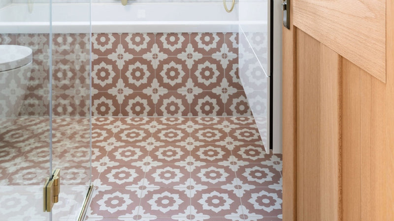 The bathroom features pink floor tiles with patterned geometric floral designs in muted pink and cream tones