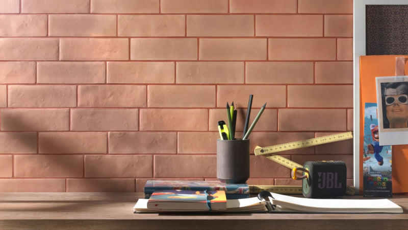 Black JBL portable speaker with textured surface and visible logo in a collection featuring pink kitchen tiles