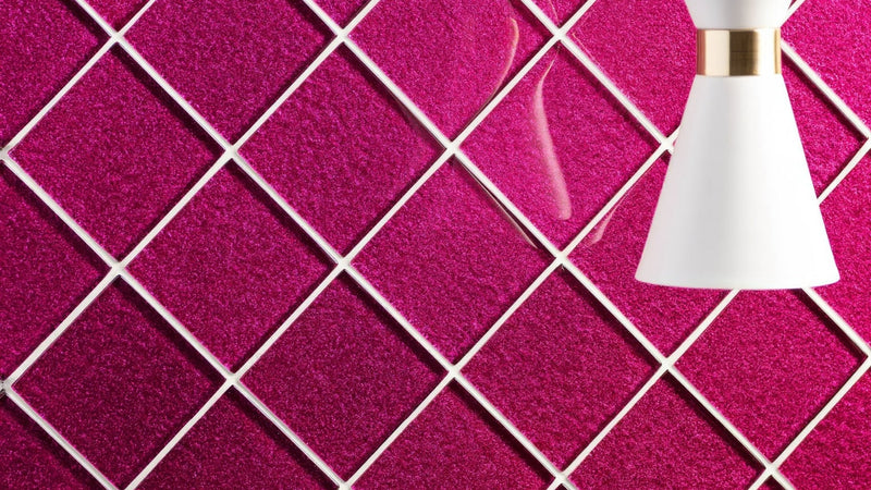 A sleek white pendant lamp with a gold accent hangs against a vibrant magenta glittery diamond patterned pink wall tiles