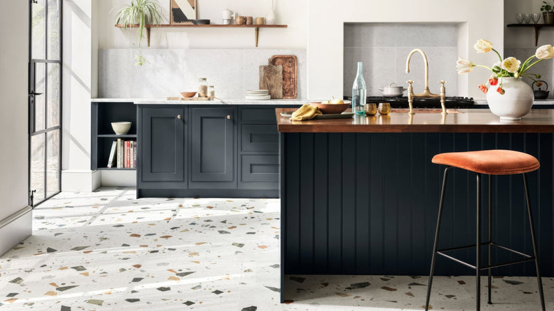 Orange upholstered bar stool with black metal legs displayed in a porcelain kitchen tiles collection