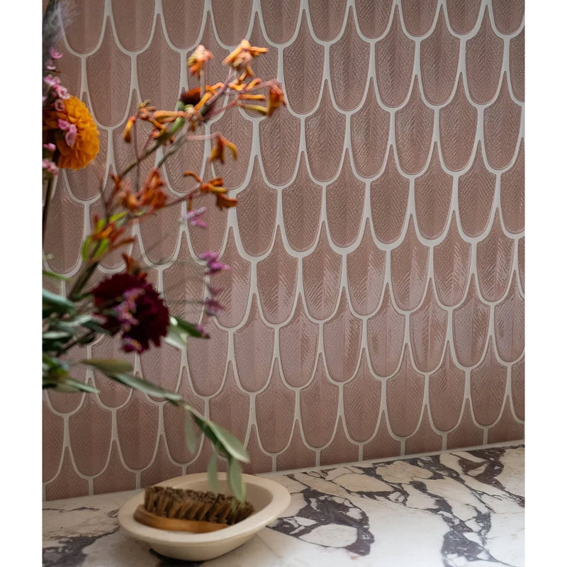 A wall with rose gold-toned scalloped porcelain mosaic tiles outlined in white from preen porcelain mosaic