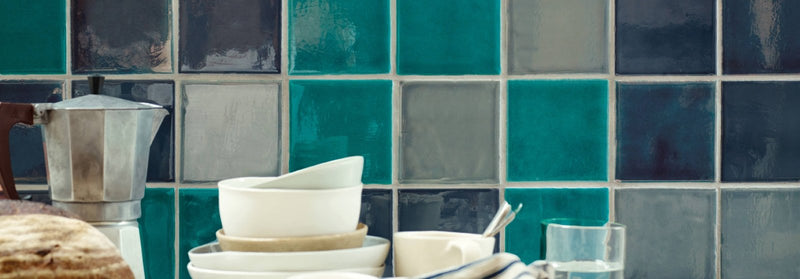 Stack of white ceramic bowls with subtle beige rim arranged neatly against teal and gray Provence tiles wall background