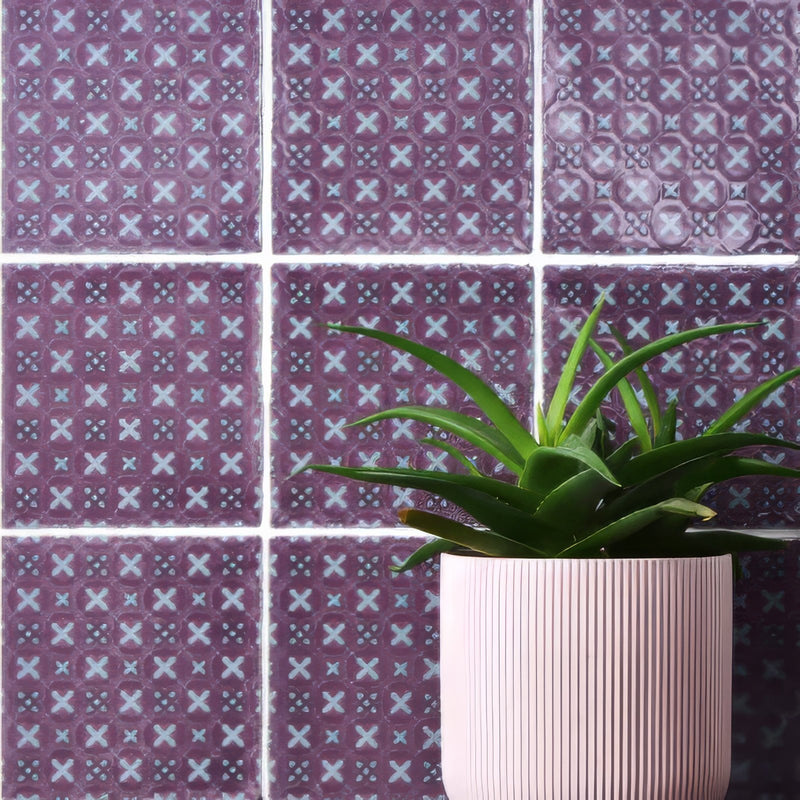 A pink ribbed ceramic planter holding a green succulent plant from the purple tiles collection