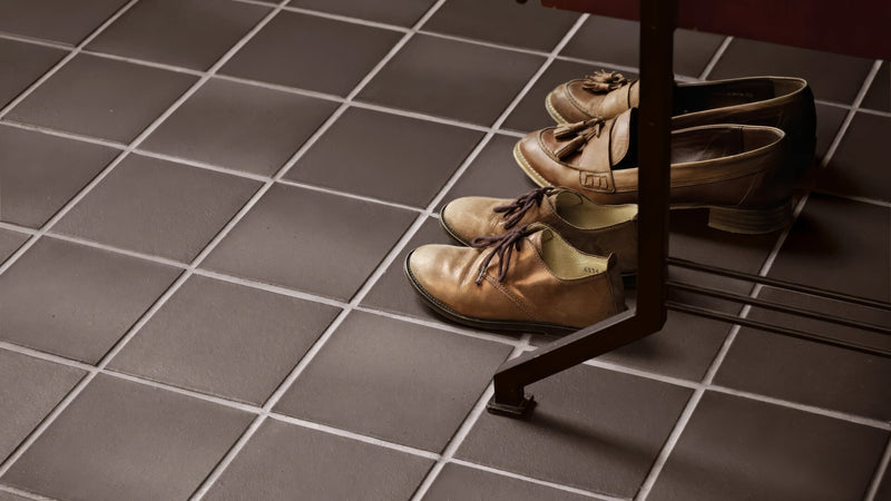 A pair of tan leather oxford shoes with dark laces and low heel under a table leg in quarry kitchen tiles collection