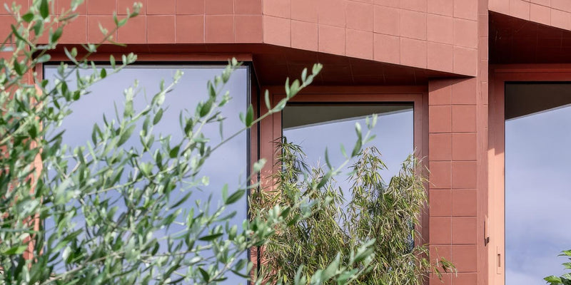 The building features modern reddish-brown quarry wall tiles with sleek glass windows on the facade.