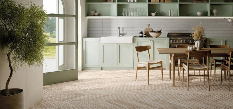Light green kitchen cabinets with white subway tile backsplash and wooden dining table and chairs in ramsbury collection