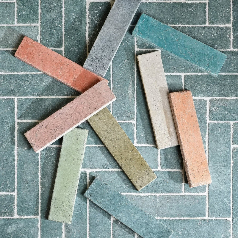 A collection of reform composite stone rectangular ceramic tiles with textured terracotta sage green and slate gray tones