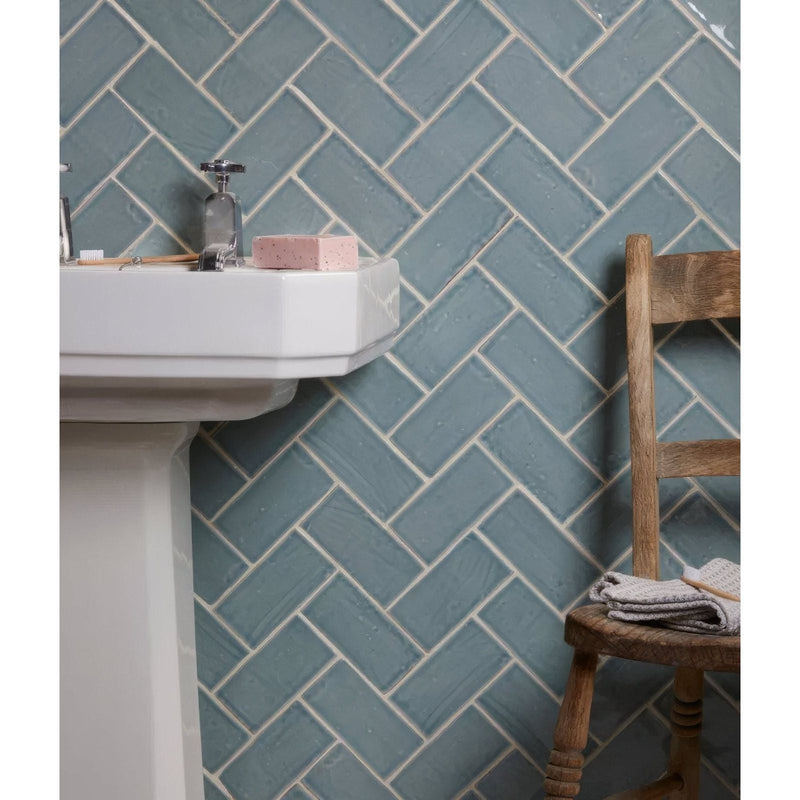 Blue herringbone patterned ceramic tiles with white grout from the Seaton ceramic collection