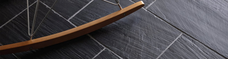 A sleek curved wooden beam with a smooth finish resting on dark gray slate tiles from the slate tiles collection