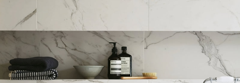 Two sleek black pump bottles with minimalist white labels on marble countertop in south beach tiles collection
