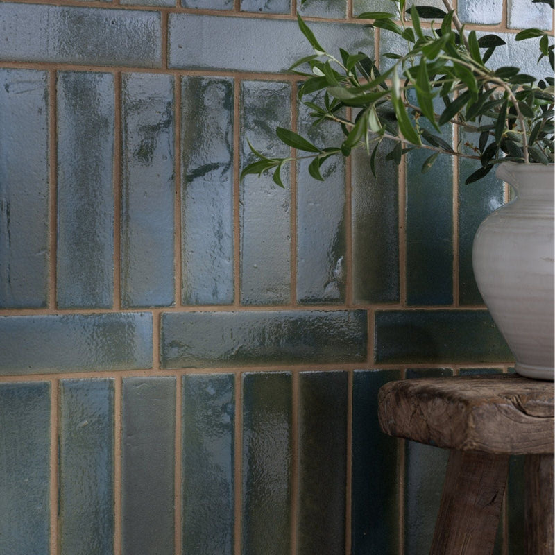 Blue green glazed ceramic tiles with textured rustic finish arranged in vertical rows from stone glaze ceramic collection
