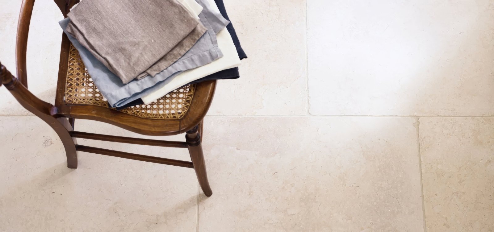 Stack of neatly folded linen napkins in muted gray blue and white tones from temple limestone tiles collection