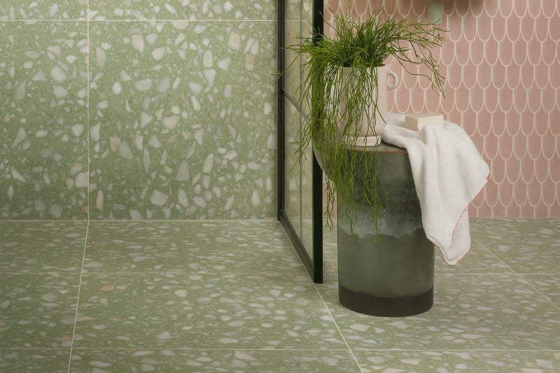 A cylindrical matte-finished ceramic planter with a dark gray to translucent green gradient in terrazzo bathroom tiles collection