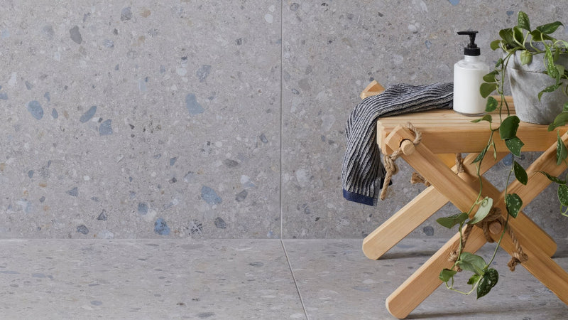 Minimalist wooden folding stool with natural light wood finish and rope-tied legs holding striped towel and potted plant