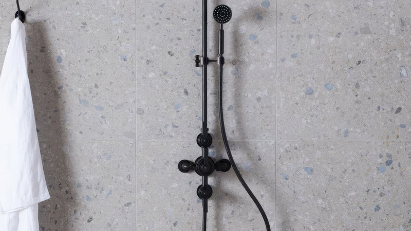 Black matte-finished shower system with modern design and adjustable handheld nozzle in terrazzo effect wall tiles collection