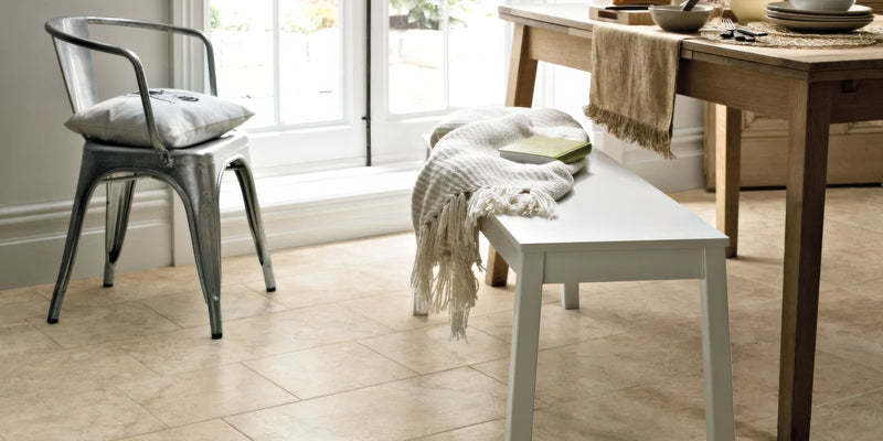 White wooden bench with textured gray throw blanket draped over it in tivoli porcelain tiles collection setting