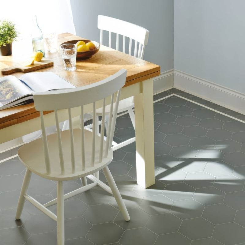 White wooden dining chair with vertical spindles and curved backrest shown from the back in victorian floor tiles buckfastleigh pattern