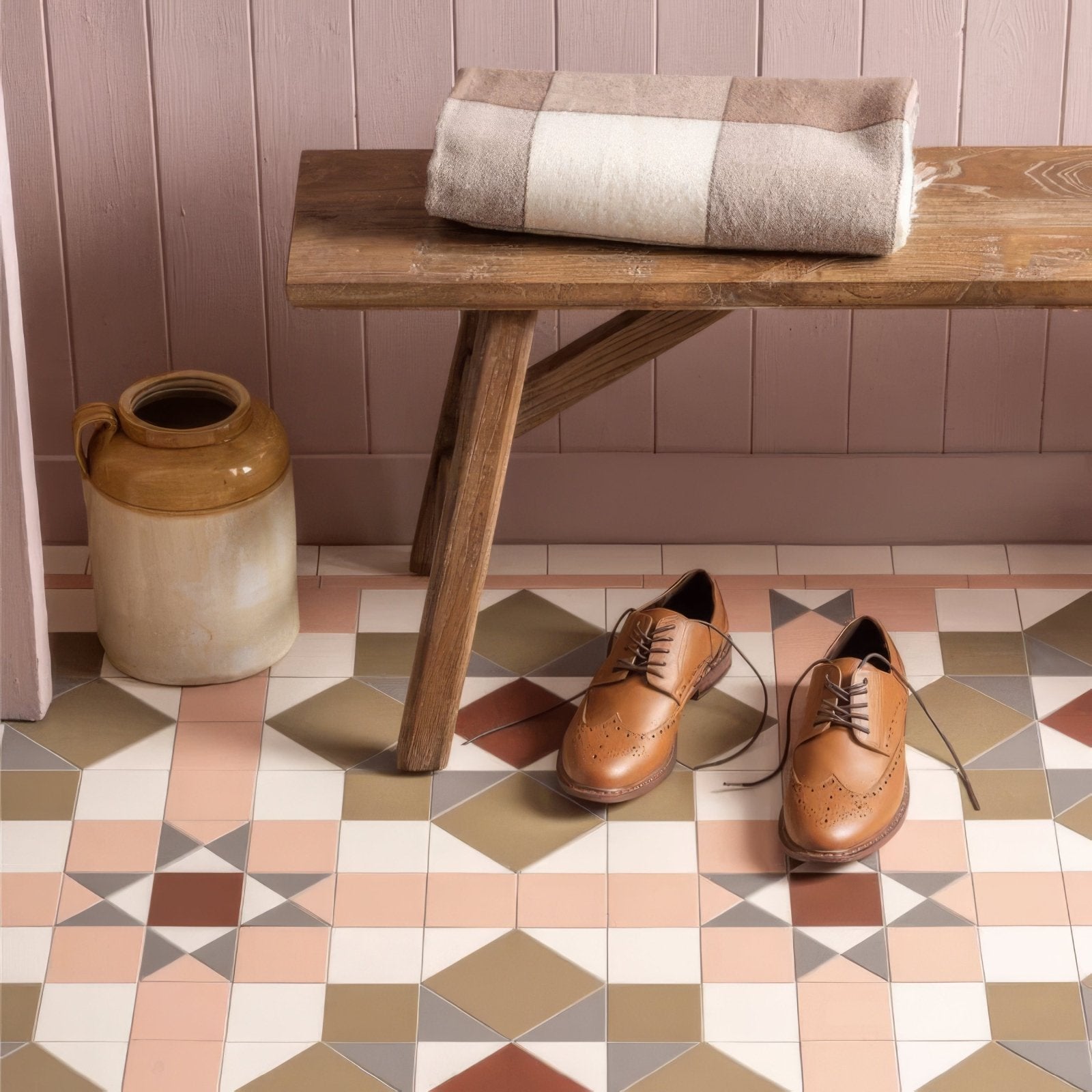 A pair of tan leather brogue dress shoes with brown laces and decorative perforations on victorian floor tiles chatsworth pattern