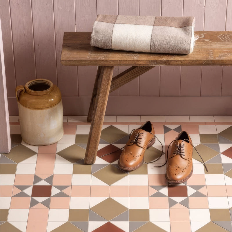 A pair of tan leather brogue dress shoes with brown laces and decorative perforations on victorian floor tiles chatsworth pattern