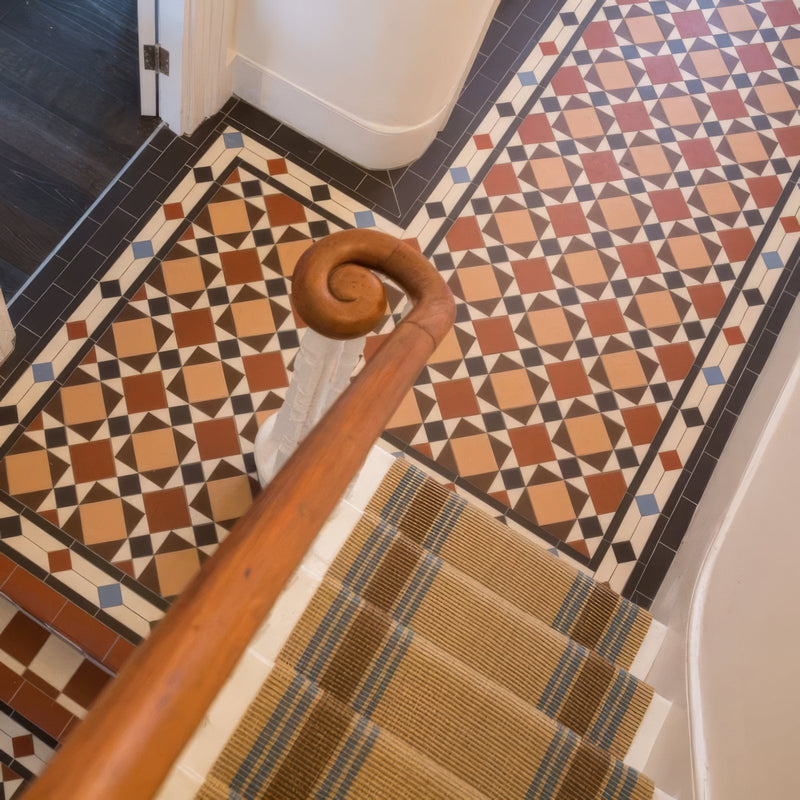 A polished wooden staircase handrail with a curved spiral top in victorian floor tiles lambeth pattern collection