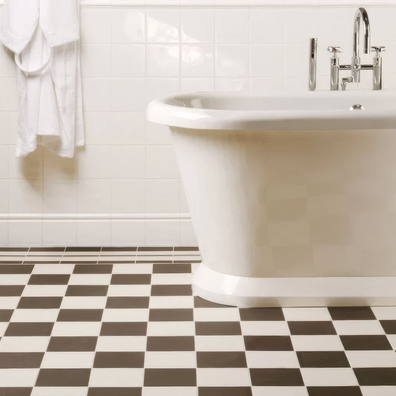 White freestanding bathtub with sleek curved design and chrome faucet fixtures on victorian floor tiles oxford pattern