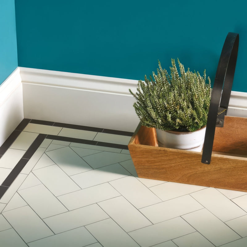A wooden planter box with a white ceramic pot holding greenery on victorian floor tiles scarborough pattern