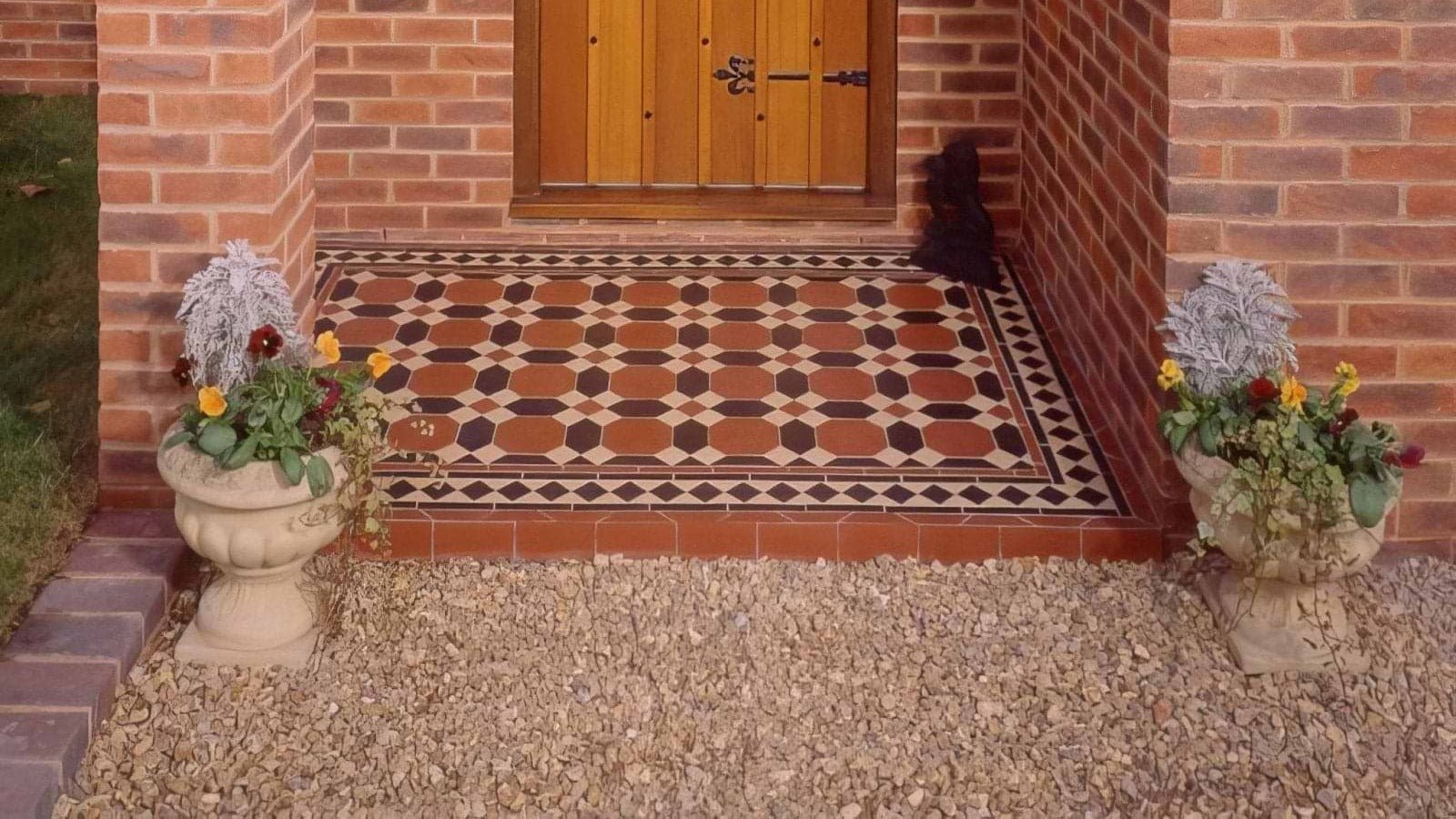 Terracotta and black octagonal victorian floor warwick pattern tiles with decorative border flanked by stone planters