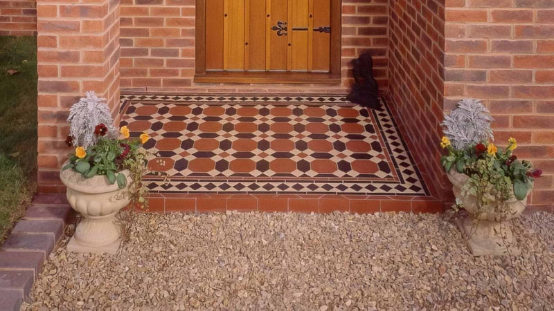 Terracotta and black octagonal victorian floor warwick pattern tiles with decorative border flanked by stone planters