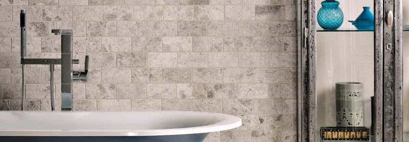 White porcelain bathtub with sleek modern chrome faucet in westhampton marble tiles collection bathroom setting