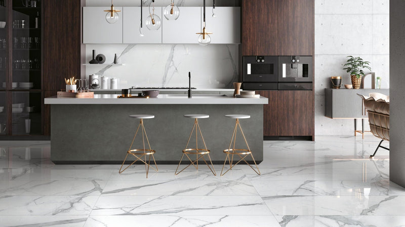 Modern kitchen island with sleek matte gray countertop and dark wood cabinetry on white floor tiles.