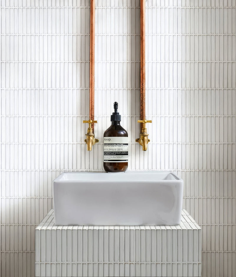 A sleek rectangular white ceramic sink with minimalist design on matching pedestal in white mosaic tiles collection