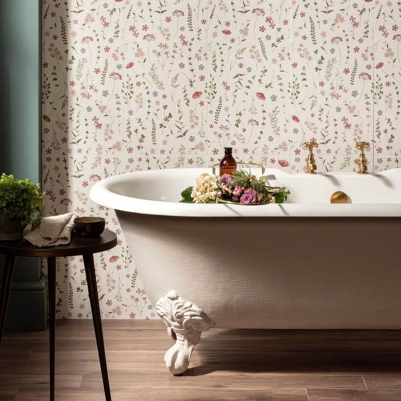 White clawfoot bathtub with gold fixtures and floral wallpaper backdrop from wildflower collection