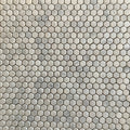 Close detail of tumbled Carrara marble hexagons showing rounded edges and a matt, faintly pitted face