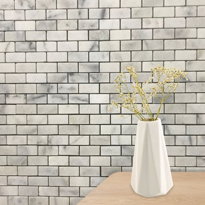 Close detail of polished Carrara marble bricks showing the veining and glossy surface