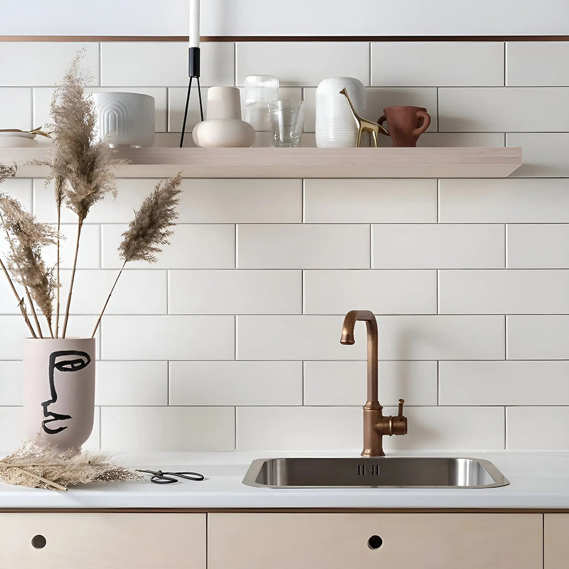 Modern kitchen with white tiled wall, wooden shelf, and stainless steel sink.