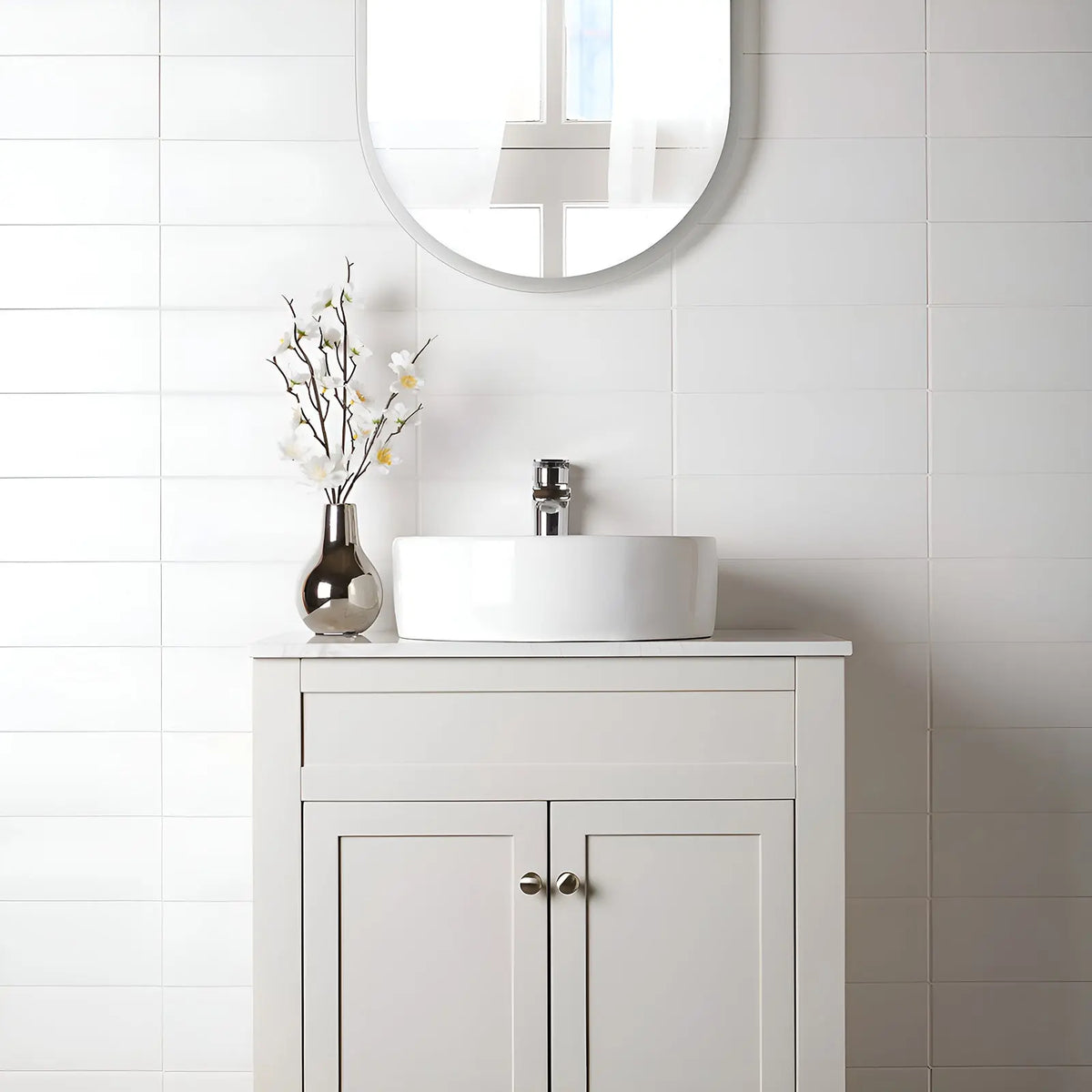 Bathroom vanity with round mirror, sink, and decorative vase on a tiled wall.