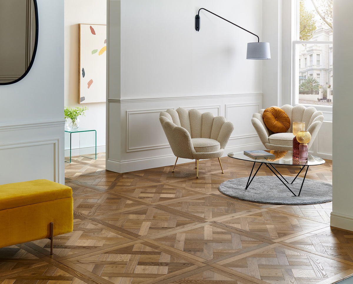 Woodpecker Sandringham Royal Oak design panel flooring in a panelled living room with velvet shell chairs