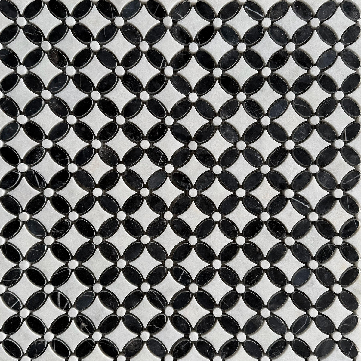 Close detail of polished Nero Marquina and Carrara petals meeting at a grout joint