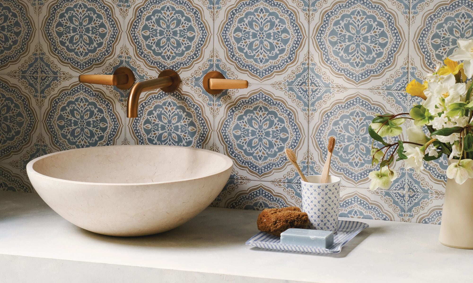 Bathroom setting with a sink, decorative tiles, and a vase with flowers.