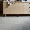 Light wood grain cabinet with gold-toned round knobs and tapered legs paired with ascoli porcelain avorio 40 x 40cm tiles